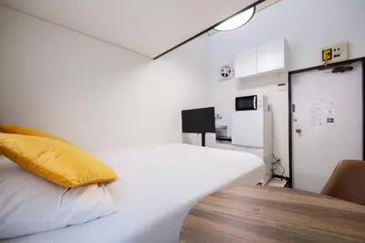 a bedroom with a white bed with a yellow pillow at \u30b0\u30ea\u30fc\u30f3 \u30d2\u30eb in Tokyo