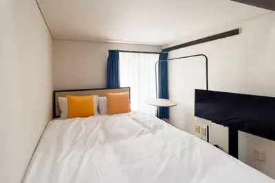a bedroom with a white bed with orange pillows at \u30b0\u30ea\u30fc\u30f3 \u30d2\u30eb in Tokyo