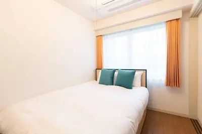 a bedroom with a white bed and a window at \u30b3\u30b9\u30e2\u30ea\u30fc\u30c9\u5357\u9ebb\u5e03 in Tokyo