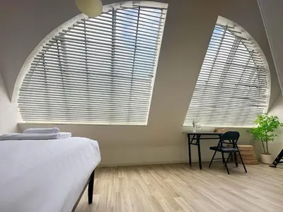 a bedroom with two large windows and a table with a chair at 7\u6642IN19\u6642OUT # \u65b0\u5bbf\u99c5\u96fb\u8eca4\u5206 # \u99c58\u5206 # \u65b0\u898f\u30ea\u30ce\u30d9\u30fc\u30b7\u30e7\u30f3 # \u6700\u59275\u540d # \u5c02\u7528\u30d0\u30b9\u30ad\u30c3\u30c1\u30f3 # 7 00 IN19 00 OUT # 4 min train to Shinjuku # 8 min walk to station # Newly renovated # Max 5 guests # Private bath kitchen in Tokyo