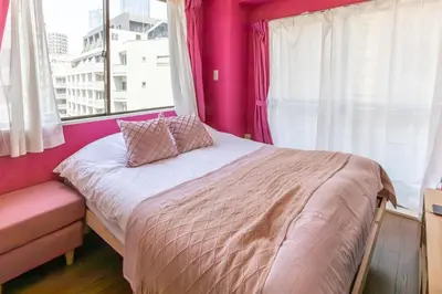 a bed in a room with pink walls and a window at Azabukumai building in Tokyo