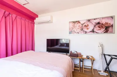 a bedroom with pink curtains and a bed and a tv at Azabukumai building in Tokyo