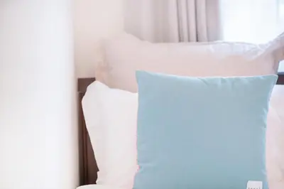 a blue pillow sitting on a bed with white pillows at walk to Higahsi Shinjuku sta. EEY in Tokyo