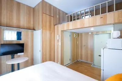 a bedroom with wooden walls and a white refrigerator at \u30d1\u30ed\u9577\u5d0e in Tokyo