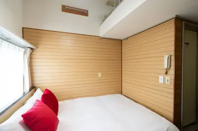 a bedroom with a bed with a wooden wall at \u30d1\u30ed\u9577\u5d0e in Tokyo
