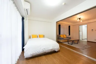a bedroom with a white bed and a living room at \u30e9\u30a4\u30ef\u30de\u30f3\u30b7\u30e7\u30f3\u5357\u9ebb\u5e03 in Tokyo