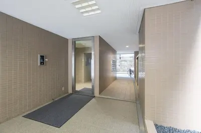 a hallway with white tile walls and a glass door at \u30e9\u30a4\u30ef\u30de\u30f3\u30b7\u30e7\u30f3\u5357\u9ebb\u5e03 in Tokyo