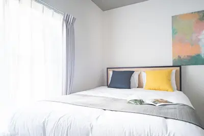 a bedroom with a bed with white sheets and a window at \u30e9\u30eb\u30fc\u30ca\u6771\u6c60\u888b in Tokyo