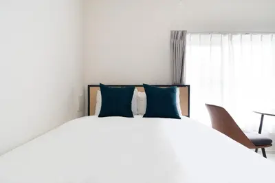 a bedroom with a large white bed with blue pillows at \u30e9\u30eb\u30fc\u30ca\u6771\u6c60\u888b in Tokyo