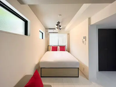 a bedroom with a bed with red pillows at \u30e9\u30eb\u30fc\u30ca\u6771\u6c60\u888b in Tokyo