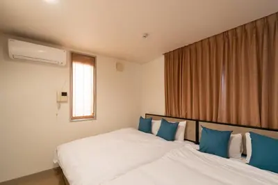 a bedroom with a large bed with blue pillows at \u6771\u99d2\u5f622\u4e01\u76ee\u6238\u5efa in Tokyo
