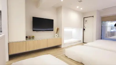 a bedroom with two beds and a tv on a wall at The Monica Residence ShinjukuGyoen in Tokyo