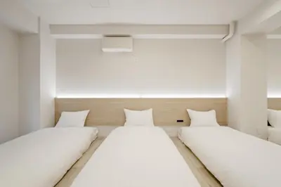 two beds in a room with white walls at The Monica Residence ShinjukuGyoen in Tokyo