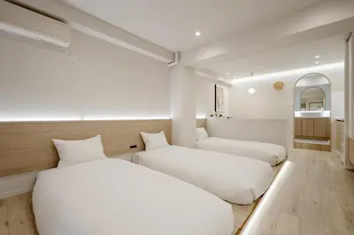 a bedroom with two beds and a couch at The Monica Residence ShinjukuGyoen in Tokyo