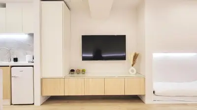 a kitchen with a tv on a white wall at The Monica Residence ShinjukuGyoen in Tokyo
