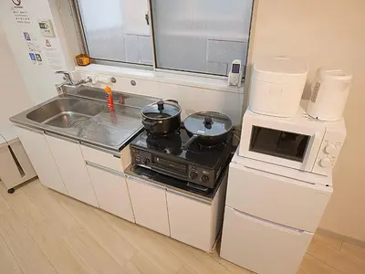a small kitchen with a stove and a microwave at \u685c\u306e\u5ddd 3\u4e28\u6b65\u884c 5 \u5206 \u5de3\u9d28\u99c5 JR \u7ebf 2-8 \u4eba \u65e5\u5f0f\u516c\u5bd3\u4e285-Min Walk to Sugamo JR Line 2-8 Guests Japanese Home in Tokyo
