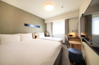 a hotel room with two beds and a desk at Richmond Hotel Tokyo Suidobashi in Tokyo