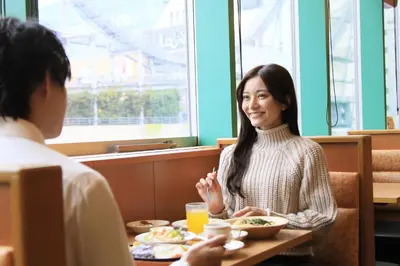 a woman sitting at a table with a man eating food at Richmond Hotel Tokyo Suidobashi in Tokyo