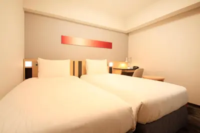 a hotel room with two beds and a table at Richmond Hotel Tokyo Suidobashi in Tokyo