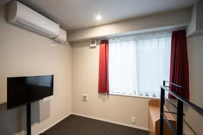 a room with a television and a window with red curtains at D-WASEDA in Tokyo