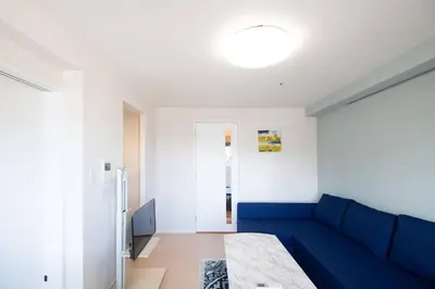 a living room with a blue couch and a door at Elegant Condominium Kinshicho in Tokyo
