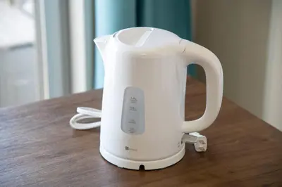a white electric kettle sitting on a wooden table at Elegant Condominium Kinshicho in Tokyo