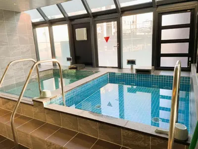 a large swimming pool in a room with windows at Men Only Capsule Room & Sauna, Bathhouse, gim 男性専用サウナ&カプセル Minami Gakugeidai in Tokyo