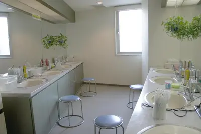 a bathroom with a row of sinks and stools at Men Only Capsule Room & Sauna, Bathhouse, gim 男性専用サウナ&カプセル Minami Gakugeidai in Tokyo