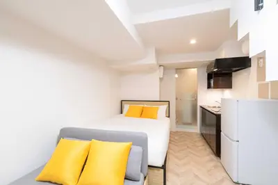 a small bedroom with a bed and a refrigerator at LaVie\u521d\u53f0 in Tokyo
