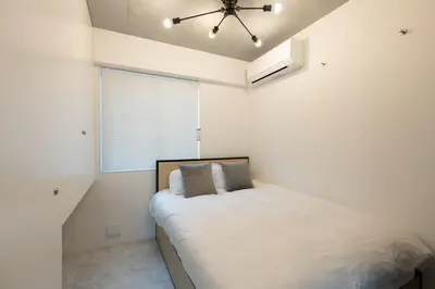 a white bedroom with a bed and a window at Luxe\u5357\u9752\u5c71 in Tokyo