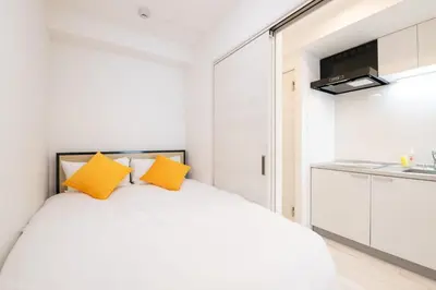 a bedroom with a white bed with yellow pillows at \u30bf\u30b9\u30adsmart\u6771\u65b0\u5bbf in Tokyo