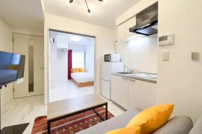 a living room with a couch and a kitchen at \u30bf\u30b9\u30adsmart\u6771\u65b0\u5bbf in Tokyo