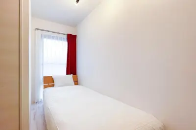 a bedroom with a white bed and a window at \u30bf\u30b9\u30adsmart\u6771\u65b0\u5bbf in Tokyo