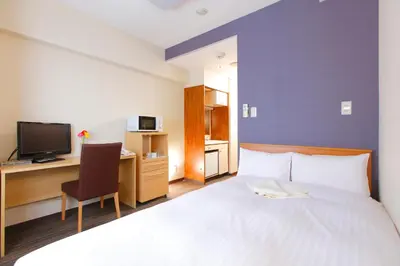 a hotel room with a bed and a desk and a tv at FLEXSTAY INN Ekoda in Tokyo