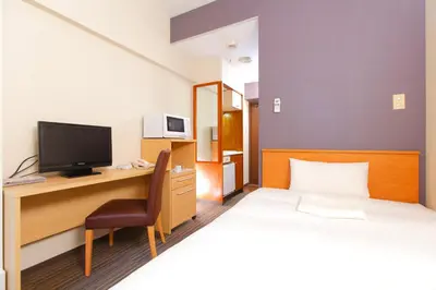 a hotel room with a bed and a desk with a television at FLEXSTAY INN Ekoda in Tokyo