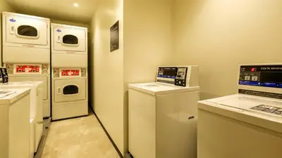 a laundry room with three washer and dryers at HOTEL MYSTAYS Higashi Jujo in Tokyo