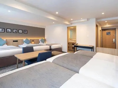 a hotel room with three beds and a table at HOTEL MYSTAYS Iidabashi in Tokyo
