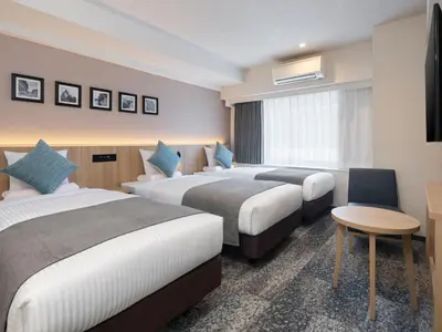a hotel room with two beds and a desk at HOTEL MYSTAYS Iidabashi in Tokyo