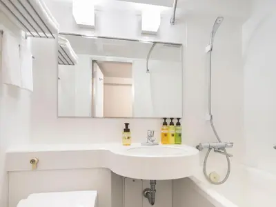 a white bathroom with a sink and a mirror at HOTEL MYSTAYS Iidabashi in Tokyo