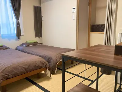 a room with two beds and a table in it at Lodging Tokyo Shibamata in Tokyo