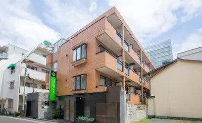 a brick building with a green sign on the side of it at FLEXSTAY INN Shirogane in Tokyo
