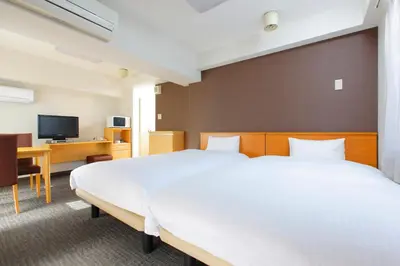 a hotel room with two beds and a tv at FLEXSTAY INN Shirogane in Tokyo