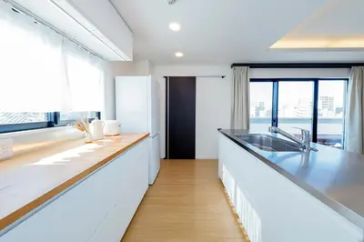 a kitchen with white counters and a large window at Kiyosumi SOHO by Tranova in Tokyo