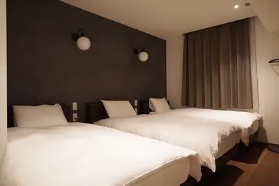 two beds in a room with white sheets at MARUKOU HOTEL in Tokyo