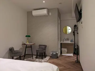a bedroom with a bed and a table and a air conditioner at MARUKOU HOTEL in Tokyo