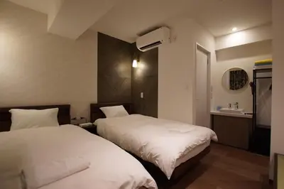 a bedroom with two beds and a sink in it at MARUKOU HOTEL in Tokyo