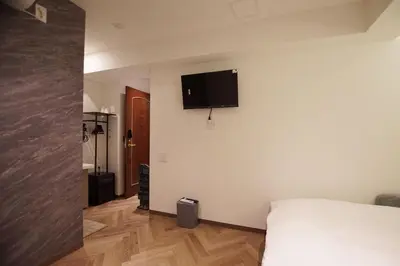 a bedroom with a bed and a flat screen tv on the wall at MARUKOU HOTEL in Tokyo