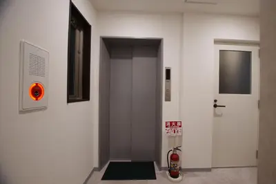 a white hallway with a door and a fire hydrant at MARUKOU HOTEL in Tokyo