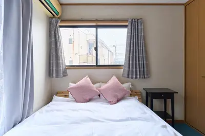 a bedroom with a bed with pink pillows and a window at 9min to kitasenju sation 6min to shopping street quiet area in Tokyo