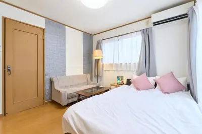 a bedroom with a white bed with pink pillows and a chair at 9min to kitasenju sation 6min to shopping street quiet area in Tokyo
